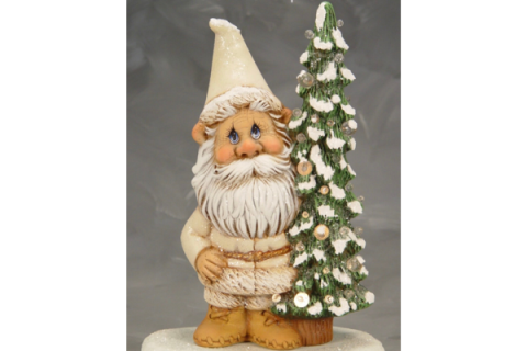 Ceramic gnome standing next to a fir tree with snow tips.